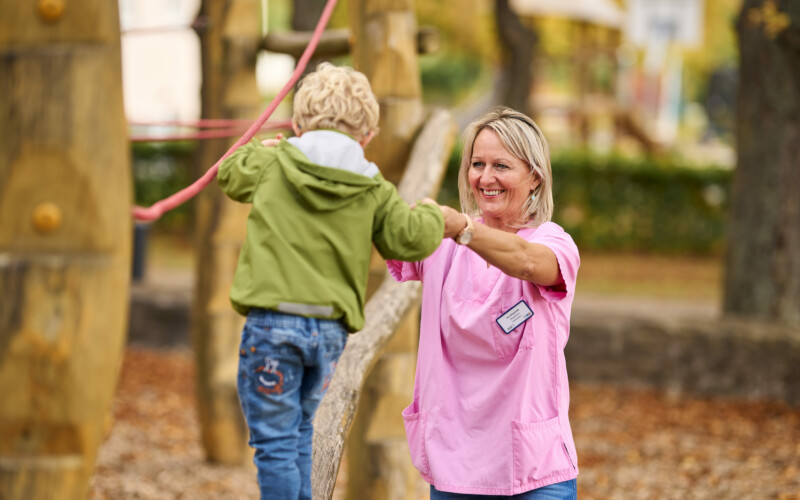 Pflegerin spielt mit Kind auf dem Spielplatz