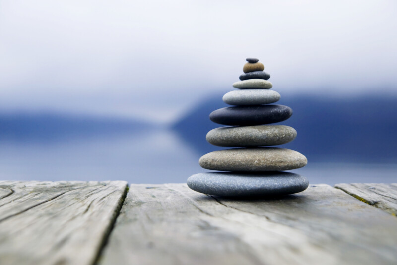 Zen balancieren von kieselsteinen neben einem nebligen see